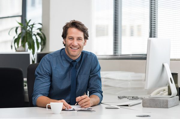 Factoring-3 Junger Arbeitgeber sitzt am Schreibtisch seines modernen Büros und blättert durch die Unterlagen für Factoring.