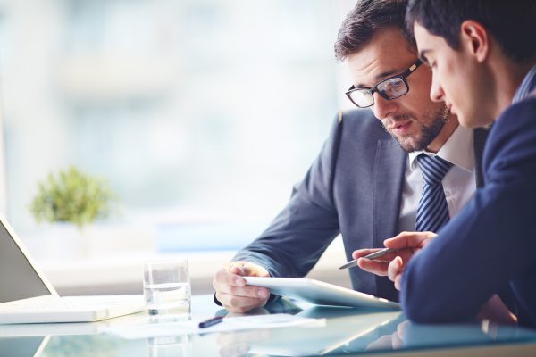 Investitionskredit-2 Zwei Unternehmer schauen gemeinsam ein Dokument bezüglich eines Investitionskredits an.