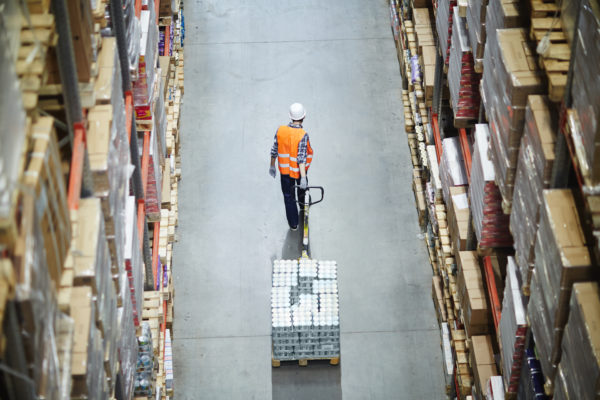 Ausschnittsfactoring-2 Factorable Ware wird von einem Mitarbeiter durch einen Gang transportiert.