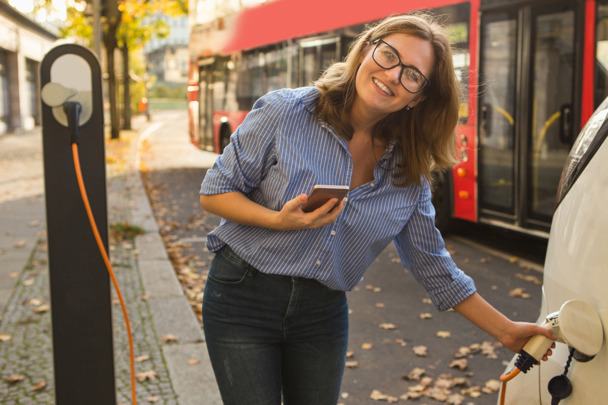 Junge Frau mit Elektroauto Elektromobilität als einer der Schlüsseltreiber in der Energiewirtschaft.