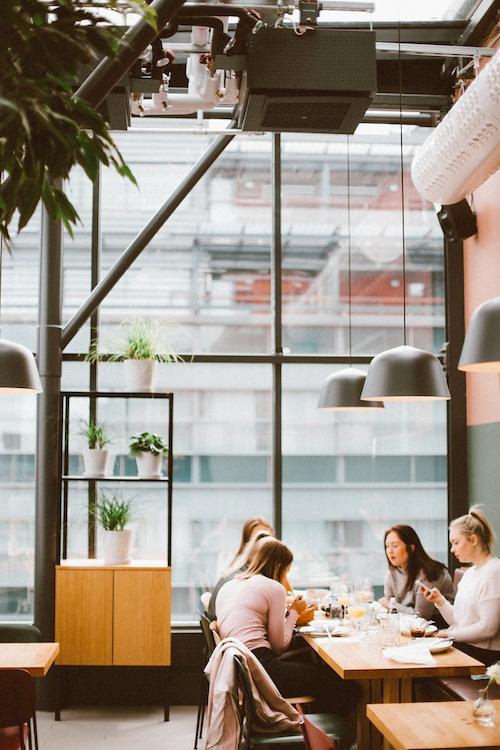 Negatives-Eigenkapital-im-Gastgewerbe Vier Frauen sitzen in einem Kaffeemit großen Glasfenstern