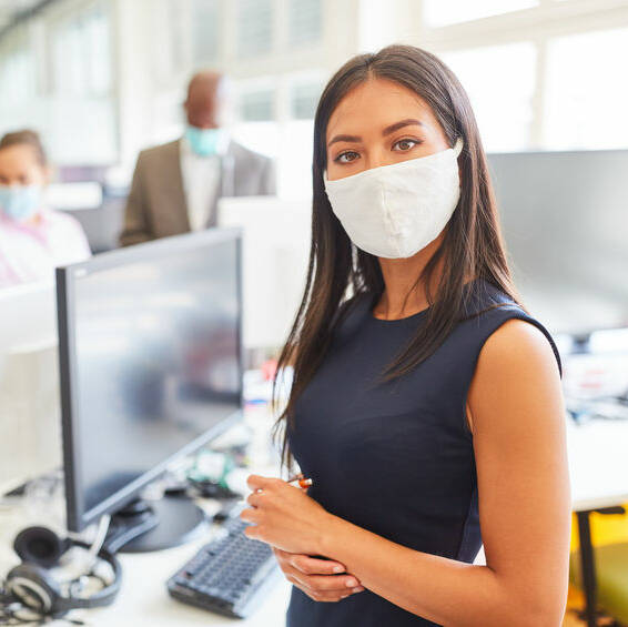 Young businesswoman with face mask as protection